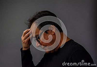 Mature man wearing glasses praying, contemplative, thinking Stock Photo