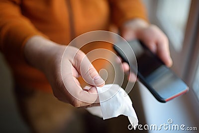 Mature man wipes with a disinfecting cloth heis smartphone after returning home. Safety during COVID-19 outbreak in public places Stock Photo