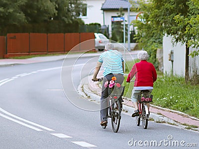 Mature man and woman rides a bicycle among the greens. A healthy and active part of life. Ecological transport for the population. Editorial Stock Photo