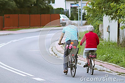 Mature man and woman rides a bicycle among the greens. A healthy and active part of life. Ecological transport for the population. Editorial Stock Photo