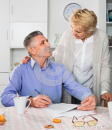 Mature married couple discuss contract and sign important docum Stock Photo