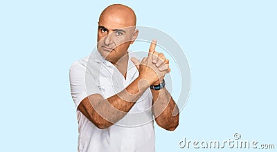 Mature middle east man with mustache wearing casual white shirt holding symbolic gun with hand gesture, playing killing shooting Stock Photo