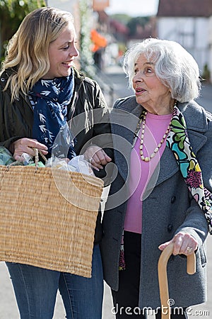 Mature Neighbor Helping Senior Woman To Carry Shopping Stock Photo