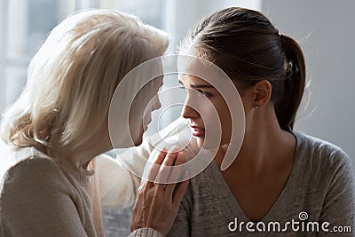 Mature older woman hugging shoulders of desperate unhappy adult daughter. Stock Photo