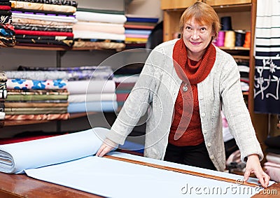 Mature saleswoman measures the fabric Stock Photo