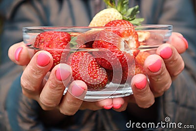 Mature strawberries in a glass Cup in women`s hands Stock Photo