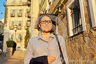 Mature successful business woman walking along city street. Stock Photo