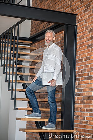 Mature tall mid-aged man standing on the stairs Stock Photo