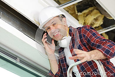 mature tradesman on stepladder making telephone call Stock Photo