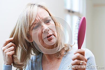 Mature Woman With Brush Concerned About Hair Loss Stock Photo