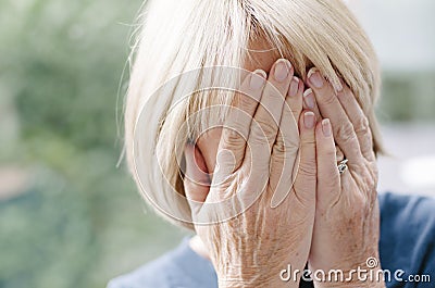 Mature woman covering her face with her hands. Stock Photo