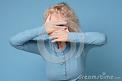 Mature woman covering her face with his hands and spies, hiding her eyes Stock Photo