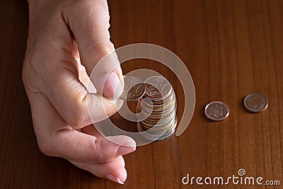 Mature woman hand putting coins into a pile on wooden table. Closeup. European euro coins, poverty concept. Counting Stock Photo