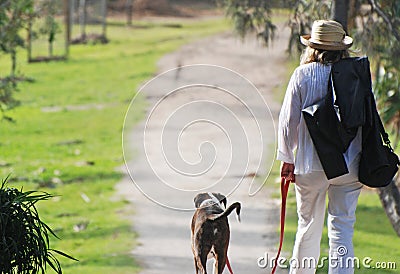 Mature woman on holiday walking pet dog Stock Photo