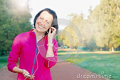 Mature woman listen music before or after jog in the park Stock Photo