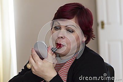 Mature woman with mirror and lipstick Stock Photo