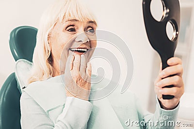 Mature woman with mirror looking at her denture Stock Photo