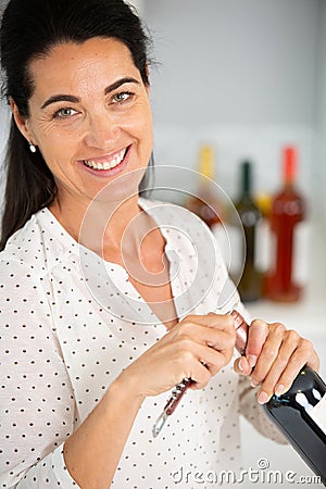 mature woman opening bottle wine Stock Photo
