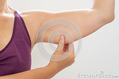 Mature woman pinching flabby arm body care and fitness concept Stock Photo