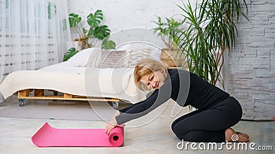 Mature woman reeling off Mat after training at home Stock Photo