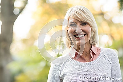 Mature woman smiling while standing in forest Stock Photo