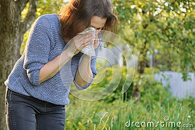 Mature woman sneezing in handkerchief, allergy to pollen, colds Stock Photo