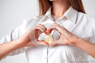 Cryptocurrency. Woman standing isolated on white holding electronic cash in heart shape close-up Stock Photo