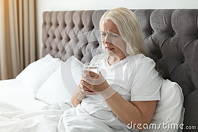 Mature woman with terrible headache holding glass Stock Photo