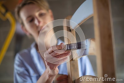 Mature Woman Upcycling Furniture In Workshop At Home Painting Wooden Chair Stock Photo