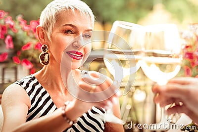 Mature woman wearing massive earrings drinking wine with husband Stock Photo