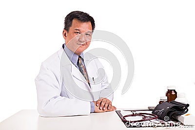 Matured Asian medical practitioner seated behind desk Stock Photo