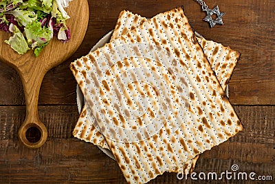 Matzah on a plate and maror on a wooden Passover board next to Magen David on a chain. Stock Photo