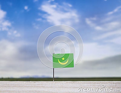 Mauritania flag with vast meadow and blue sky behind it. Stock Photo