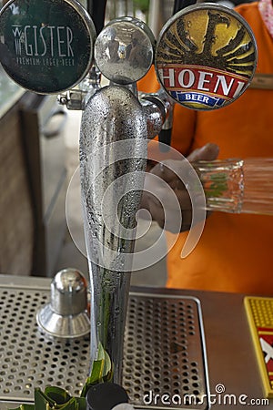 Beer dispenser with barman holding a glass Editorial Stock Photo