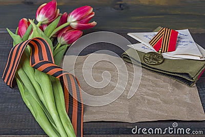 9 May background - George ribbon, note paper, red flowers front-line letters, military cap and orders on the wooden background. Stock Photo