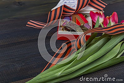 9 May background - George ribbon, red flowers front-line letters, military cap and orders on the wooden background. Victory day or Stock Photo