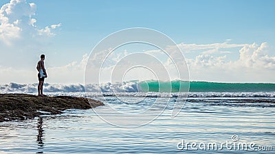 Person watching as a large wave breaks at a popular surf spot in Bali Editorial Stock Photo