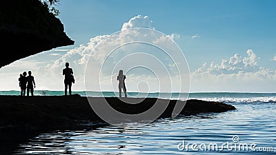 Silhouetted people watch as surfers get some nice waves in Bali Editorial Stock Photo