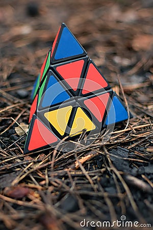 May 30, 2022, New York, USA: Triangular Rubik's Cube in the shape of a pyramid lies on brown pine needles in nature Editorial Stock Photo