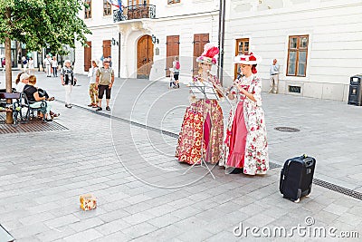 Two women street performers in medieval dresses playing on flutes Bach`s works for donations Editorial Stock Photo