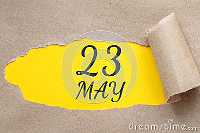 may 23. 23th day of the month, calendar date. Hole in paper with edges torn off. Yellow background is visible through Stock Photo