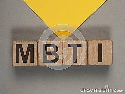 MBTI acronym on wood cubes on gray and yellow background. Psychological test Stock Photo