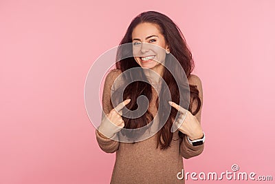 This is me, I am awesome! Portrait of happy young woman with brunette wavy hair pointing herself and smiling excitedly Stock Photo