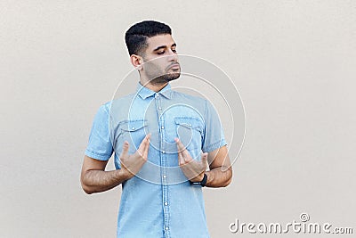 This is me. Portrait of proud handsome young bearded man in blue shirt standing, pointing, showing himself and looking with Stock Photo