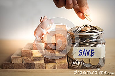 Meaning of saving money concept with piggy bank looking at holding hand with coin Stock Photo