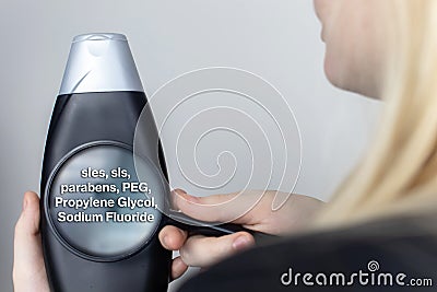 A woman examines the harmful ingredients of the shampoo a magnifying glass. Means with parabens, sls, sles. The concept of Stock Photo