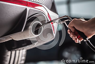 Measurement of exhaust emissions at the technical inspection station. A car repairman applies a probe to the exhaust Stock Photo