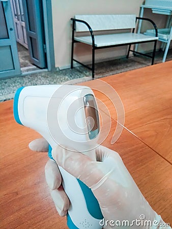 Measuring body temperature with a thermal imager in a clinic, a testing device in the hands of a nurse with gloves Stock Photo