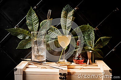 Measuring cup with ice, yellow cocktail, tweezzers and red syrop Stock Photo