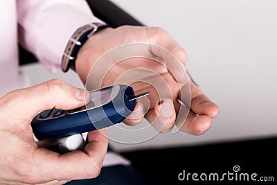 Measuring glucose level blood test using ultra mini glucometer and small drop of blood from finger and test strips Stock Photo